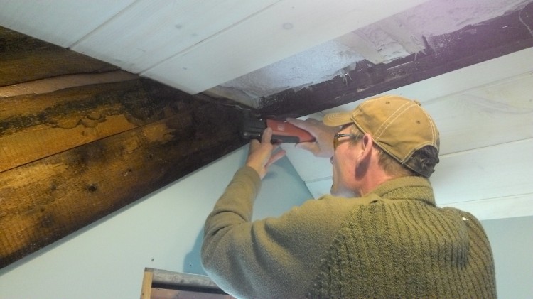 Hans uses a fine tool to cut a recess for the last row of ceiling boards.